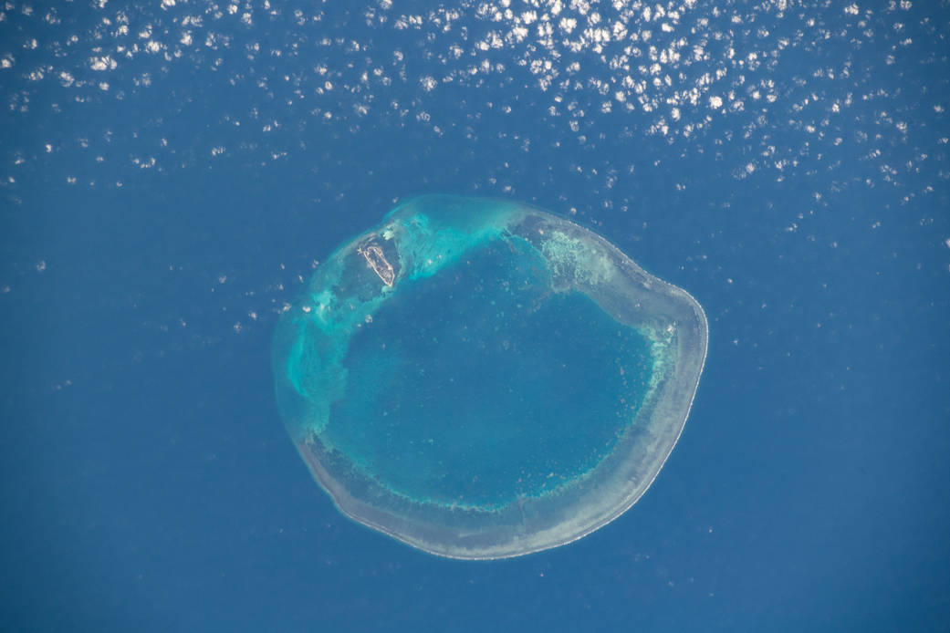 Dongsha Atoll photographed from the International Space Station, showing its coral reef and lagoon in the South China Sea.